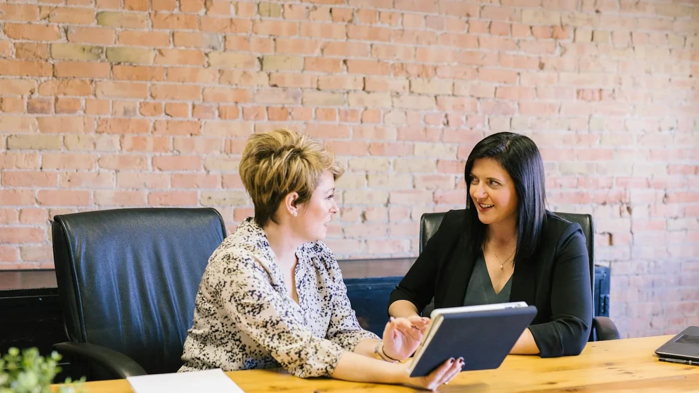 Two colleagues discussing a plan together at a meeting table