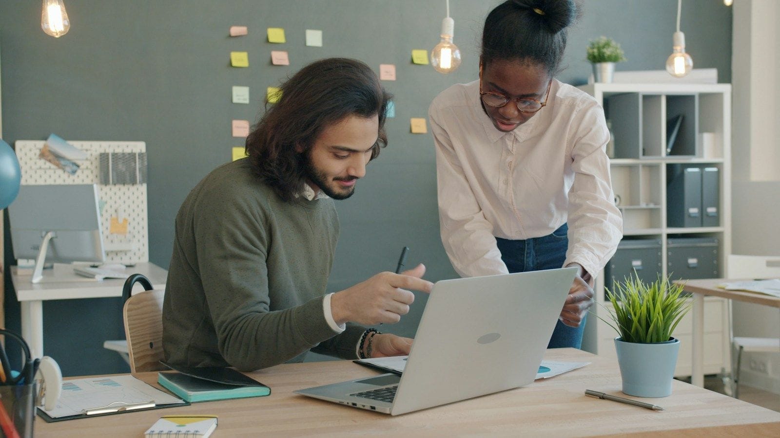 Two colleagues reviewing work together at a laptop in an office