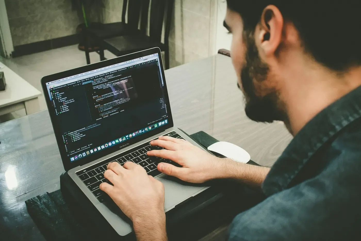 Person typing code on a laptop beside a window.
