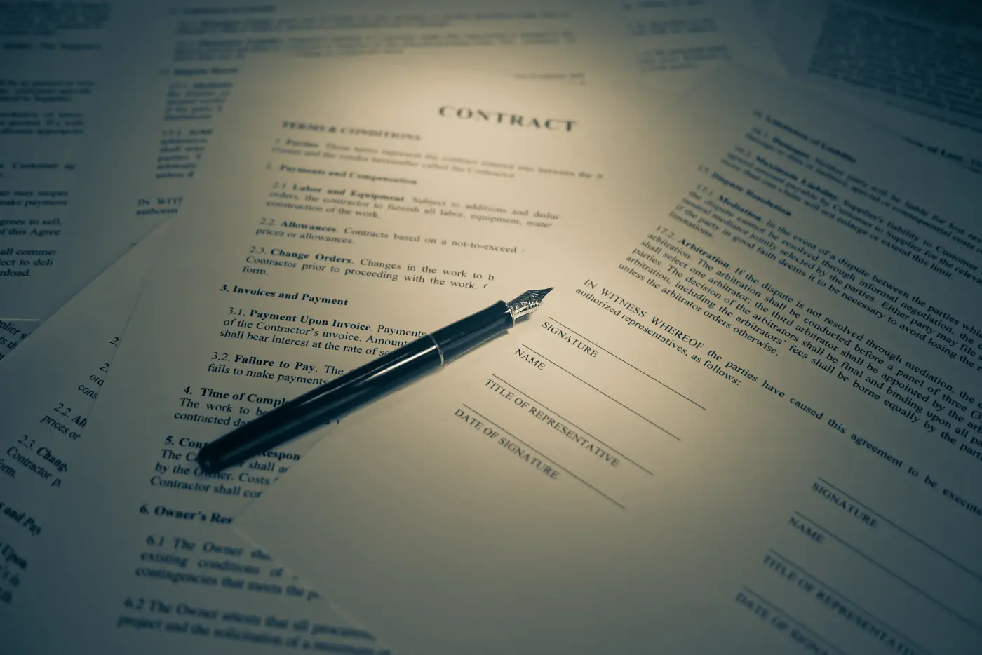 A fountain pen resting on printed contract pages headed Contract, beside blank signature, name and date lines, in warm low light.