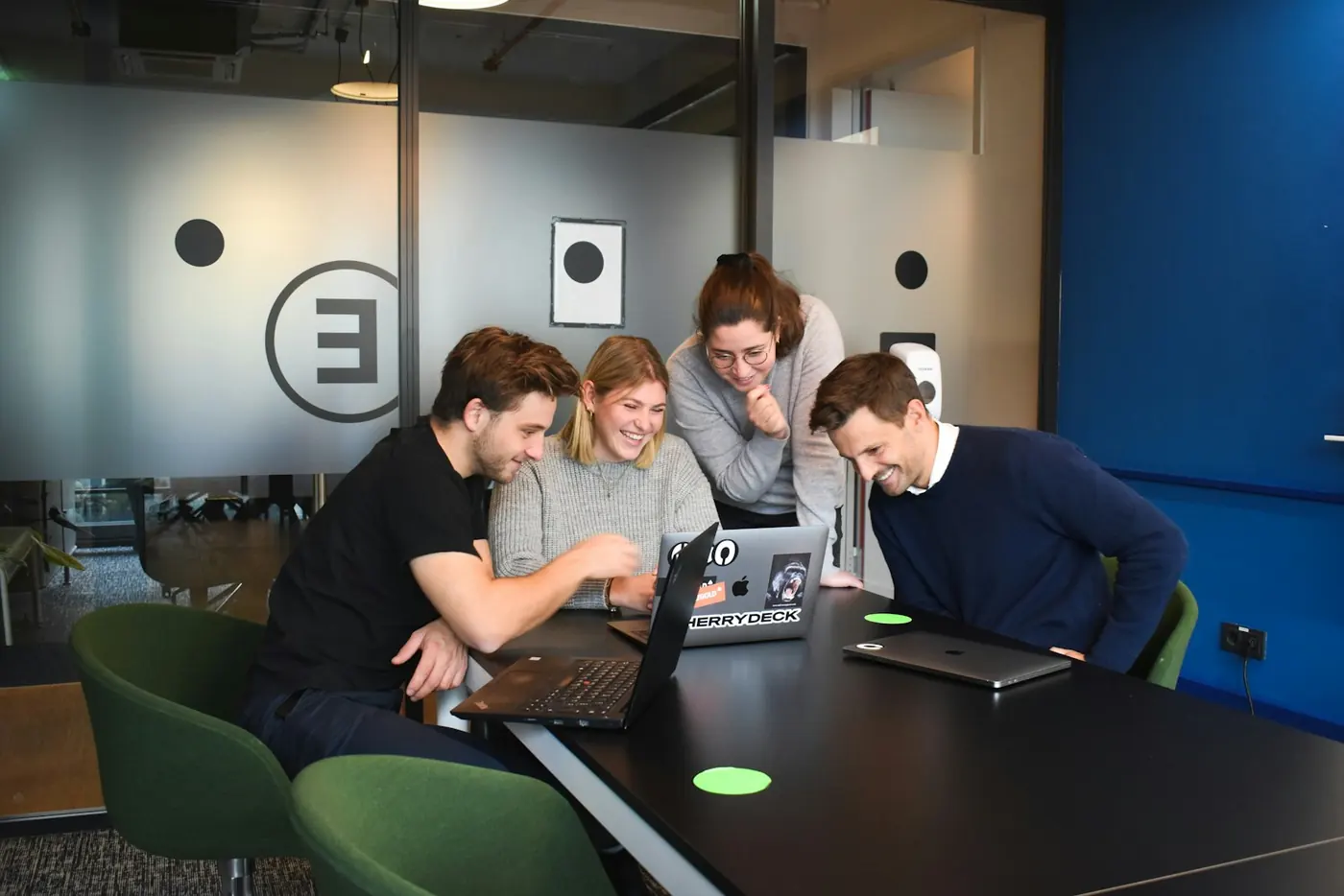 Four people leaning over a laptop during a discussion.