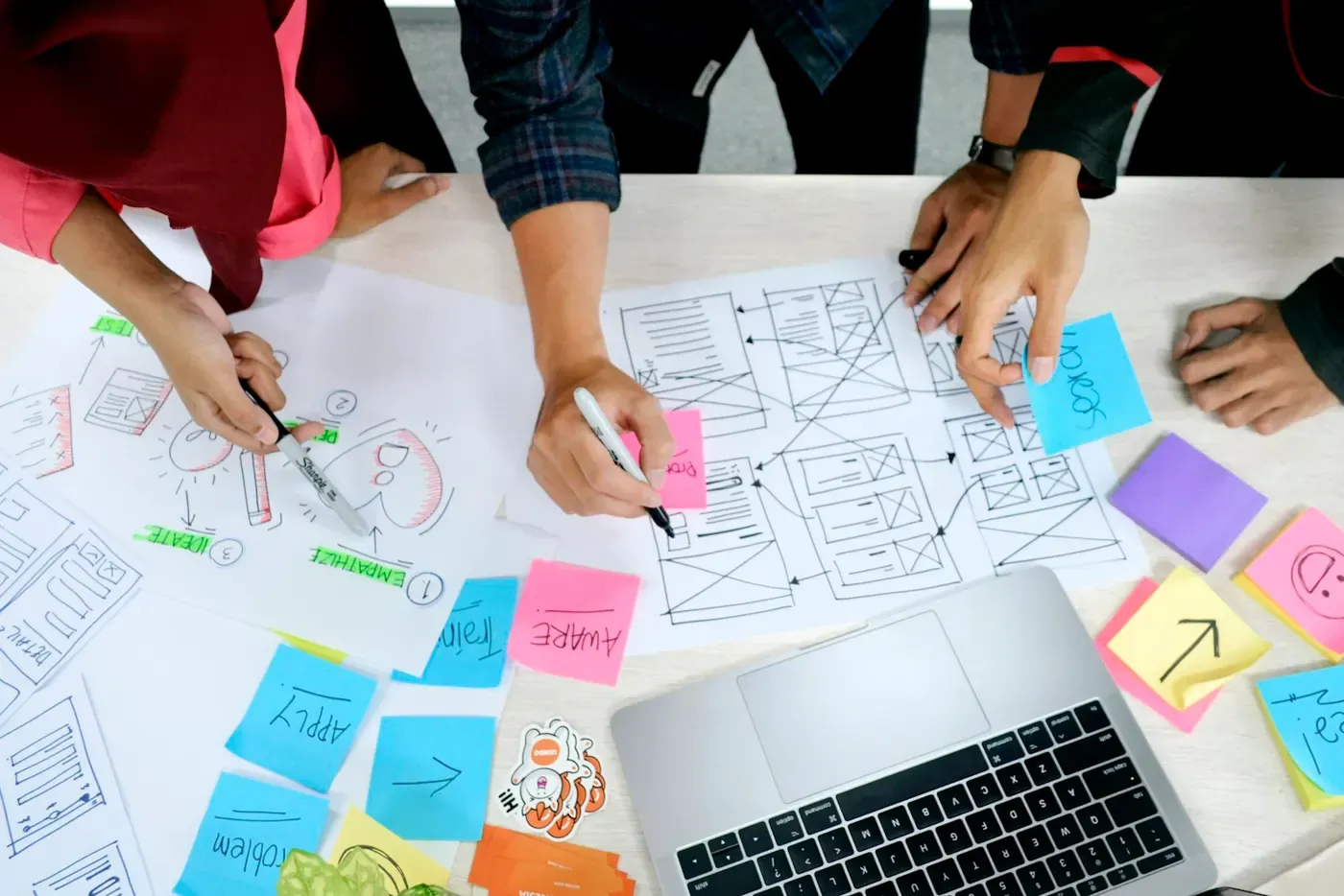 Hands sketching website wireframes with colourful notes.