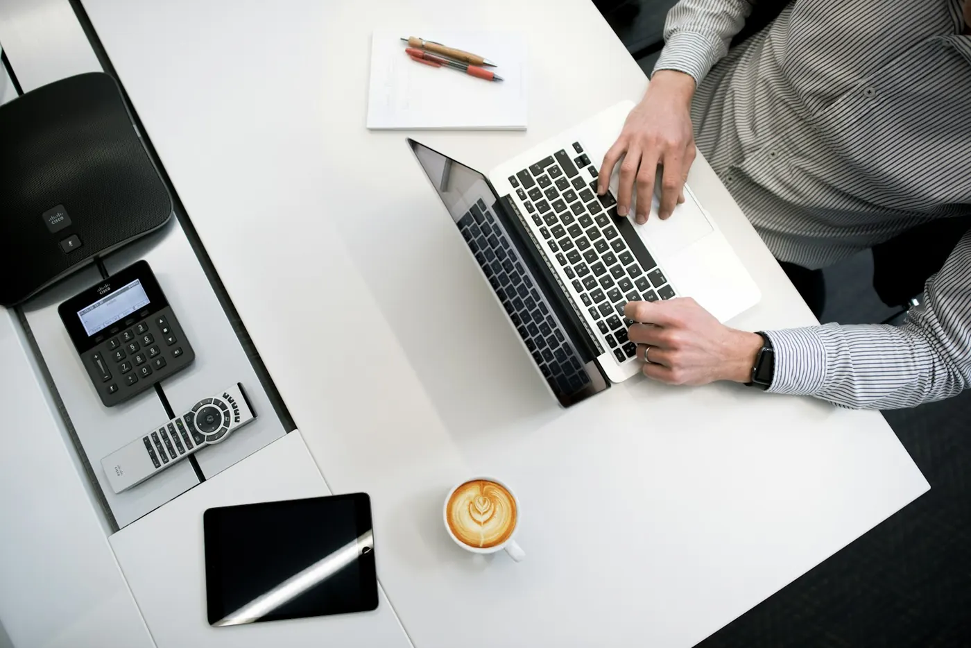 Overhead view of a person typing on a laptop at a white desk.